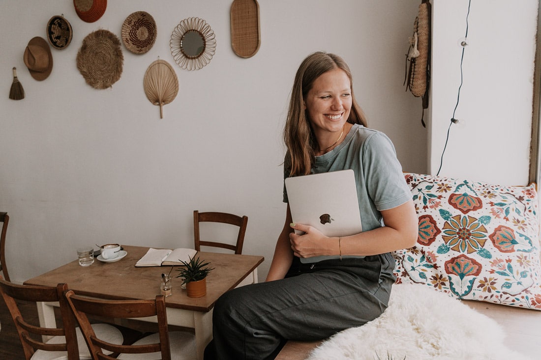 Laura Lichter sitzt auf Fensterbank mit Laptop